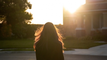 Woman looking ahead into the sunset around suburban homes